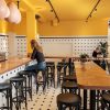 Super-Seat | Intérieur du Bentwood Café | Le café présente des tabourets de bar Thonet noirs sur un comptoir en bois, avec des murs jaunes et un sol en damier. | Mobilier de restauration