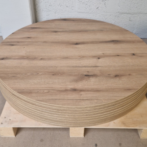 Super-Seat | Une palette avec une pile de plateaux de table | Finition mélaminée Castle Oak, motifs de grain de bois, charme rustique contre un mur de briques blanches. | Mobilier de restauration