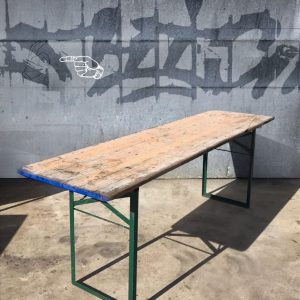 Super-Seat | Tables pliantes vintage | Plateau de table en bois rustique, pieds en métal vert, sol en béton, graffiti sur le mur avec une main pointée. | Mobilier de restauration