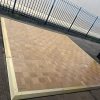 Super-Seat | Le Mobiele dansvloer, houten vloer met messing rand ca. 15m2 | Lichtbruin geblokt houten dansvloer met messing rand, gelegd op beton naast blue metalen hek. | Horecameubilair