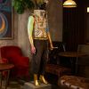 Super-Seat | Wastelander #4 | Zwartleren fauteuils, planten, duistere lounge; pop met gouden handen/voeten, zwart textiel, papieren hoed. | Horecameubilair